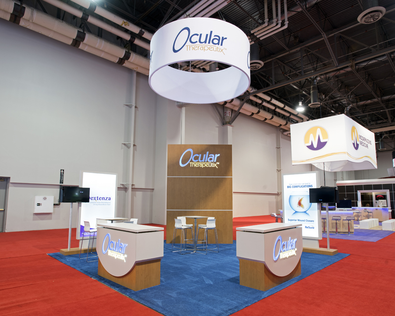 Ocular Therapeutix custom exhibit with round fabric hanging sign, counters and two monitors stands out on the show floor.