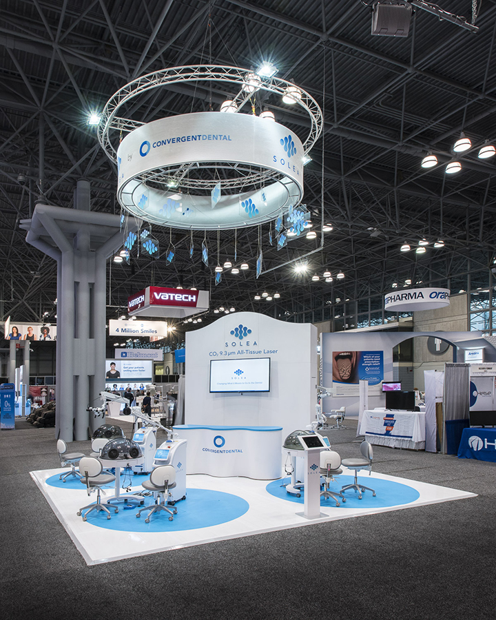 A 20x20 custom exhibit with storage, hanging fabric structure, hands-on demo stations and large mounted monitors